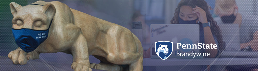 Penn State Brandywine. Penn State Nittany Lion Shrine wearing protective mask. Masked Students in campus computer lab in background. 