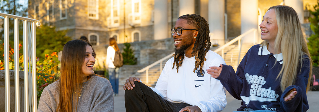 Penn State University Park. A group of students enjoying a conversation on the steps of icon old main.